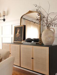 a mirror sitting on top of a dresser next to a vase