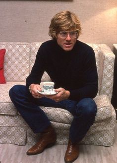 a man sitting on top of a couch holding a white plate in his hand and looking surprised