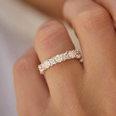 a woman's hand with a wedding band on it and three stones in the middle