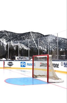 an ice hockey rink with mountains in the back ground and snow on the mountain behind it