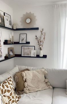 a white couch sitting in a living room next to two shelves with pictures on it