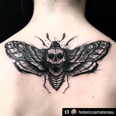 a woman's back with a skull and moth tattoo on it