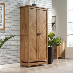 a wooden cabinet sitting in front of a brick wall next to a potted plant