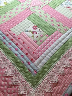 a pink and green patchwork quilt on a bed