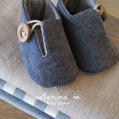 pair of baby shoes sitting on top of a blue cloth covered place mat with wooden buttons