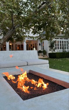 a fire pit in the middle of a yard with a couch and trees behind it