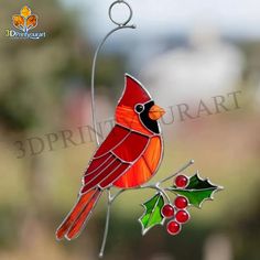 a stained glass cardinal ornament hanging on a branch with holly berries and leaves