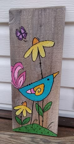 a painted wooden block with a bird and flowers on the front porch, next to a house