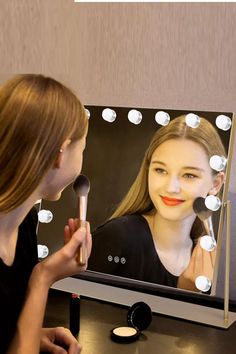 a woman is looking at herself in the mirror with her makeup brush and foundation powder