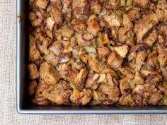 a casserole dish with meat and vegetables in it sitting on a cloth covered table