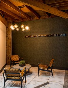 two chairs and a table in front of a wall that says god is still writing your story