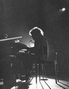 a woman sitting at a piano in the dark