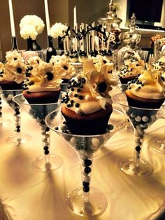 several cupcakes are sitting in wine glasses on a table with candles and flowers