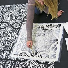 a woman is working on an intricately designed piece of art that she has made