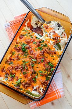 a casserole dish with meat and vegetables in it on a napkin next to a fork