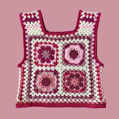 a pink and white crocheted bag with flowers on it's side, against a pink background