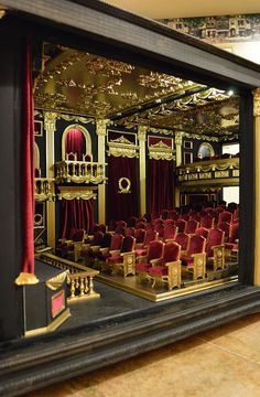 an ornately decorated theater with red velvet seats and gold trimmings is reflected in the mirror