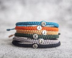 four bracelets with letters on them sitting on top of a table next to each other