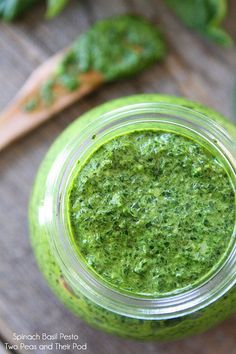 spinach basil pest in a jar on a wooden table with spoons and parsley