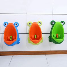 three frog shaped urinals mounted to the wall