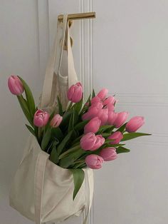 a white bag with pink and white tulips hanging on the door handle,