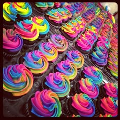 cupcakes with rainbow icing are on display