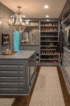 a walk in closet filled with lots of shoes and chandelier hanging from the ceiling