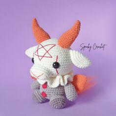 a crocheted stuffed animal with horns on it's head, sitting in front of a purple background