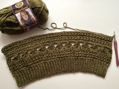 a green crochet piece next to a ball of yarn