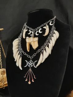 Have a Look at This Gorgeous Real Tooth and Bone Necklace! It is Made with 16 Real Raccoon Teeth, and a Large Cow Tooth in the Center, Some Stainless-Steel Crescent Moon Charms. It Has Two Real Mink Jawbones Hanging to the Sides of the Big Tooth. Underneath it all is a Wiccan Triple Moon Pendant and a Starburst Pendant. The ENTIRE Necklace is Stainless Steel! It is Adjustable to 22 Inches. All Items Ship Within 1-3 Days via USPS Ground Advantage Service. Shipping on these will be 5.50 (USA Only) All additional items are FREE! International Shipping Will Be 22.00 + 2.00 For each Additional Item. Canada 20.00 + 2.00 For each Additional Item. International Shipping May Take 2 - 6 Weeks to Deliver I DO NOT Carry Human Bones or Any Sort of Illegal Items. And As Etsy Sellers, We Are Not Allowed Satanic Costume, Raccoon Teeth, Fang Necklace, Doctor Necklace, Starburst Pendant, Tooth Pendant, Big Teeth, Human Bones, Witch Doctor