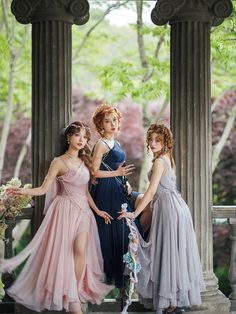 three young women in dresses posing for a photo on some steps with trees and bushes behind them