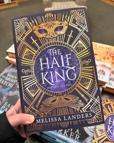 a person holding up a book in front of some books on a table with other books