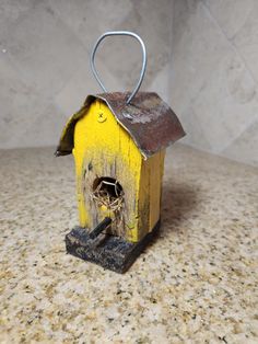 a yellow birdhouse with a hole in it's roof sitting on a counter