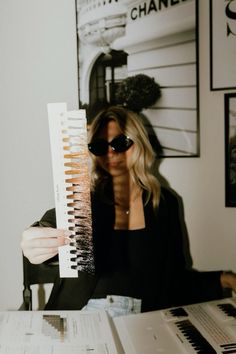 a woman sitting at a table holding up a piece of paper