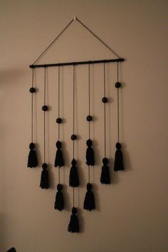 a group of black tasselled objects hanging on a wall next to a white wall