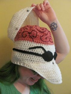 a woman with green hair wearing a crocheted hat that has a red and white stripe on it