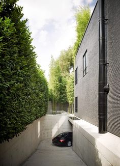 a car is parked in the narrow alley between two buildings with trees on either side