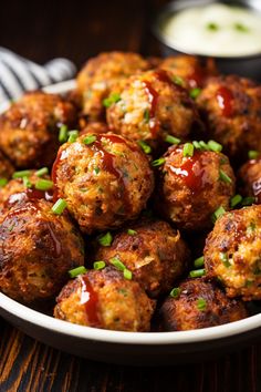 a bowl filled with meatballs covered in ketchup and garnished with green onions