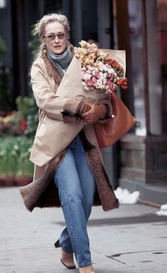 a woman walking down the street carrying flowers