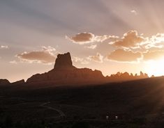 the sun shines brightly through the clouds above some rocks and mountains in the desert