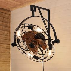 an old fashioned fan with lights on it in the corner of a room next to a wood paneled wall