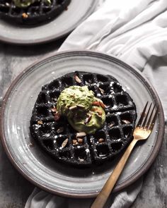 two waffles topped with guacamole and nuts on a plate next to a fork