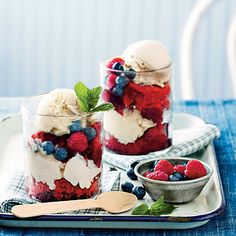 red, white and blue desserts in glass jars on a tray with spoons