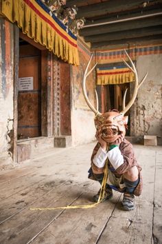 a young boy is dressed up as a deer with antlers on his head and holding something in his hands