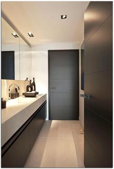 a bathroom with a sink, mirror and lights on the wall next to the door