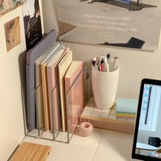 a laptop computer sitting on top of a desk next to a pile of books and papers