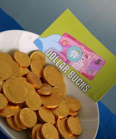 there is a bowl full of gold coins next to a small package of dollar bills