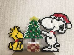 a cross stitch christmas ornament with a dog and a cat next to a tree