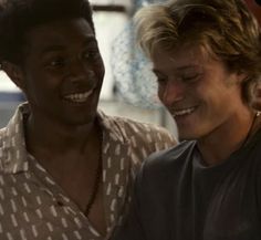 three young men standing next to each other looking at a cell phone in front of them