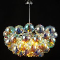 a chandelier made out of glass balls hanging from a metal rod on a black background